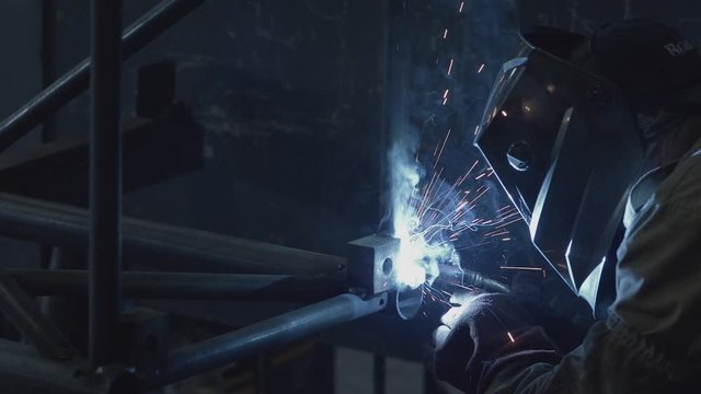 Welder working on a pipe structure, using MIG welding procedure.