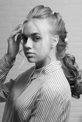 A pretty blonde in a striped shirt straightens her hair close-up.