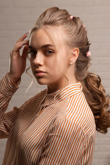 A pretty blonde in a striped shirt straightens her hair close-up.