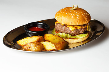 burger on a mirror plate with sauce and a potatoes