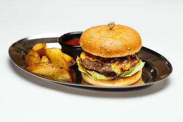 burger on a mirror plate with sauce and a potatoes