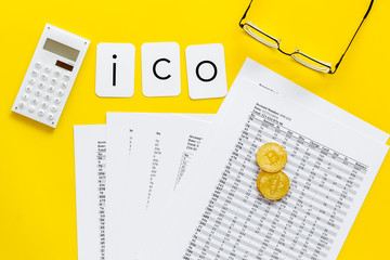 ICO with coins and calculation table on office desk yellow background top view