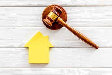 Inscribed gavel, house figure for inheritance concept on white wooden background top view