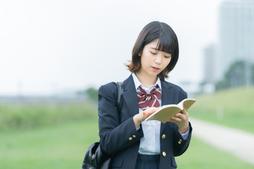 屋外で読書する女子高生