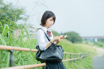 屋外で読書する女子高生