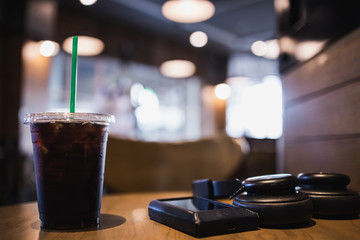 Takeaway cup of ice americano coffee with headphones and music players  in cafe