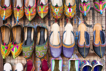 Obraz premium Beautiful and colorful traditional Rajasthani shoes hang in a shop in Jaipur. Mojari or Khussa or Saleem Shahi's is a style of handcrafted footwear produced in Rajasthan, India