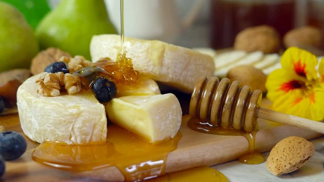 Camembert and brie cheese board with honey, fruit and nuts.