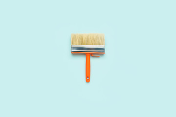 Wide paint brush on a pastel turquoise background. Work tool of the painter to create a trendy interior. Repair and room design minimal concept. Flat lay, top view.