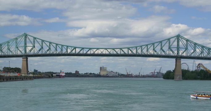 A wide shot of Jaques Cartier Bridge in Montreal, Quebec.The river in the foreground, a boat passes by across the frame. Captured in 4K in Canada.