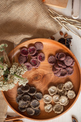Assortment of sweets without sugar and gluten on a wooden dish. Dessert made from healthy natural ingredients. Beautiful composition of healthy diet candies and flowers