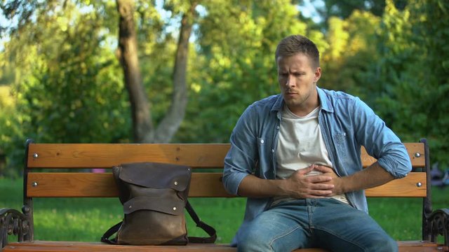 Man relaxing on bench, suddenly feeling strong stomach ache, gastritis problem