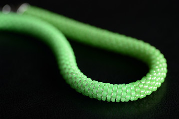 Beaded necklace light green color on a dark background close up