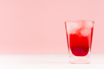 Tropical refreshment alcohol red shot drink with ice cubes on white wood board and pastel pink...