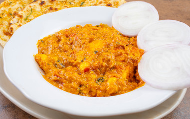 Indian Vegetarian Cuisine Special Sweet And Spicy Paneer Pasanda or Stuffed Paneer Curry, Delicacy Consisting of Stuffed Paneer with Rich Creamy Gravy Served With Garlic Naan on Vintage Background