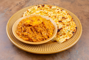 Indian Vegetarian Cuisine Special Sweet And Spicy Paneer Pasanda or Stuffed Paneer Curry, Delicacy Consisting of Stuffed Paneer with Rich Creamy Gravy Served With Garlic Naan on Vintage Background