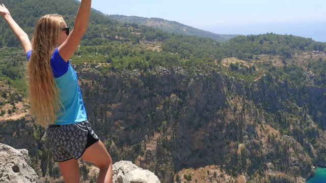Young woman enjoying freedom and taking sun bath with beatiful viewn of Butterfly Valley on background in Turkey