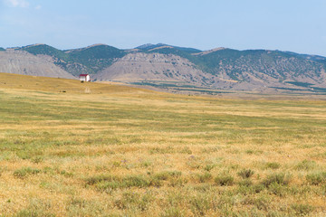 Obraz premium lonely house in the steppe at the foot of the mountains