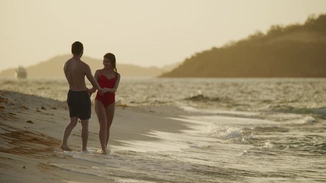 Slow motion of romantic couple holding hands walking on beach and kissing / Petit Tabac, Tobago Cays, St. Vincent and the Grenadines