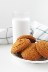 Milk glass and biscuit cookies with kitchen cloth on light background