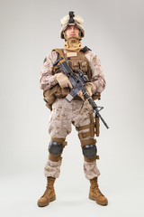 Soldier in US marines uniform with rifle on light grey background, studio shot