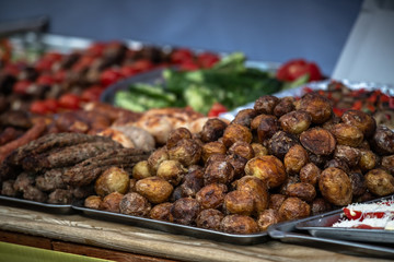 Ukrainian country fair cooking roasted potatoes cooked outdoors cookout vegetable meals fresh organic, healthy snack cooked on grill flame. Street fast food.