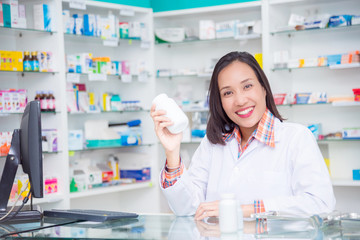 Beautiful asian pharmacist standing in drugstore and smiling at camera
