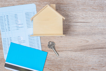 Book bank with house model and key on wood table background with copy space. Financial, money, refinance, Real estate and new hone concept