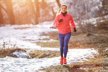 Young slim woman jogging in winter park