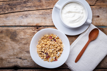Healthy breakfast background. Muesli with yoghurt in bowl on wooden background