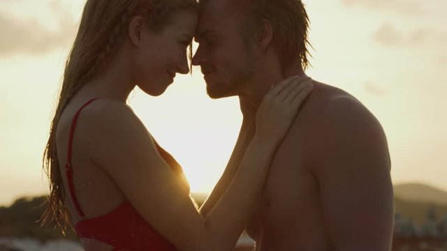 Close up of romantic couple kissing on beach at sunset / Petit Tabac, Tobago Cays, St. Vincent and the Grenadines