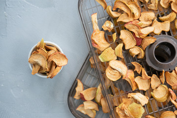 Dried apple slices in a handmade bowl and fresh apples