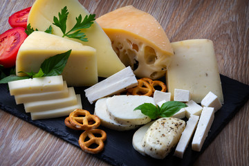 Assortment of various types of cheese on a black stone plate. copy space