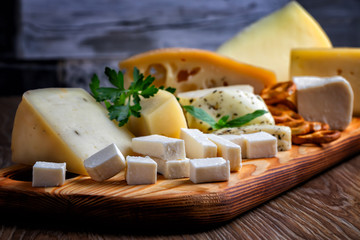 Different types of cheese on a wooden cutting board
