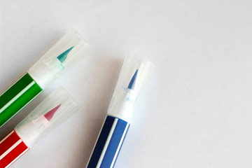 Red green blue felt-tip pens lie on a white sheet