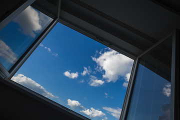 An open window overlooking the urban landscape on a sunny cloud day