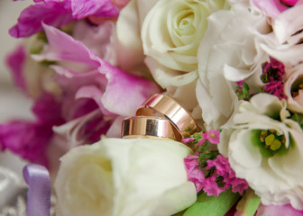 Gold wedding rings lie on the bouquet for the bride. Wedding rings in a rose. Wedding accessories