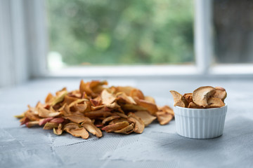 Dried apple slices in a handmade bowl and fresh apples