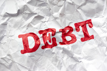 Wrinkled white paper with the word debt printed in red. Concept of debt free life or financial freedom.	