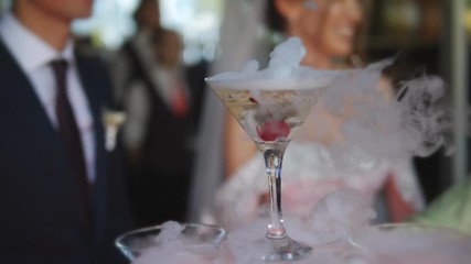 Hill champagne for the Bridal celebration smokes from dry ice on the background of the bride and groom in a blur.
