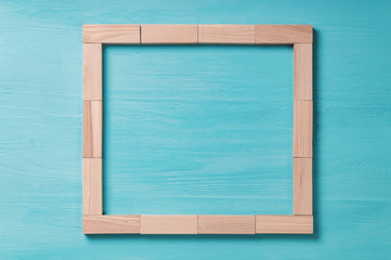 square frame, made of wooden blocks on a blue background wooden texture top view