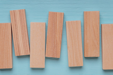 wooden blocks are arranged vertically with different angles, on a blue wooden background, top view, place for your text or advertising slogan