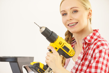 Woman on ladder using drill