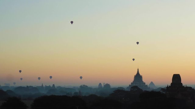 Landscape of silhouetted hot air balloons at early beautiful sunrise with temples in the background in Bagan, Myanmar