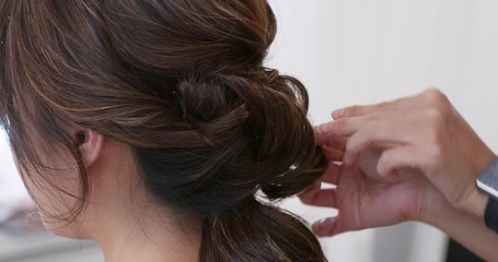 Hairdresser creating a hairstyle for bride in salon