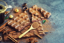 A bar of milk chocolate on the table. Chocolate with nuts and cinnamon.