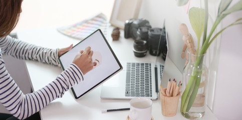 Close-up view of professional designer drawing her project with tablet in modern workplace