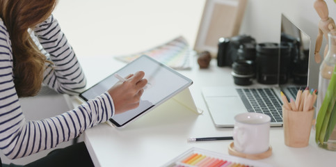 Professional designer editing her project with tablet in modern workplace