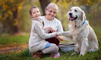 Autumn. Closeup portrait of happy grandmother with granddaughter and their favourite cute dog