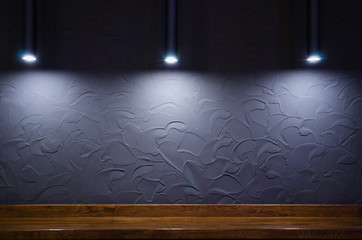 Modern design of dark gray wall with abstract pattern, three lamps and wooden surface